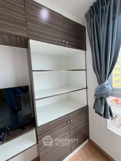 Modern living room with stylish built-in shelving and large window with curtain