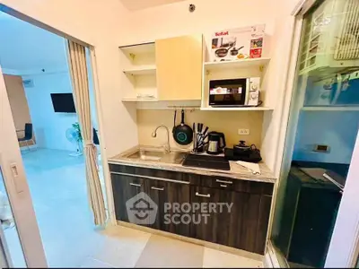 Modern compact kitchen with sleek cabinetry and appliances in a cozy apartment setting.