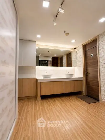 Modern bathroom with dual sinks and wooden flooring in a stylish apartment.
