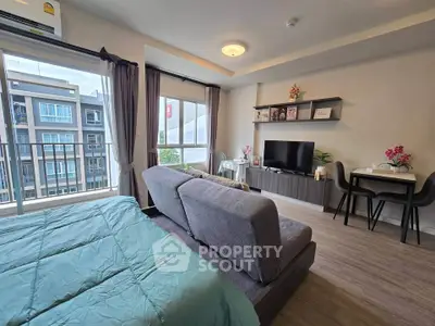 Modern studio apartment with cozy living area and large windows for natural light.