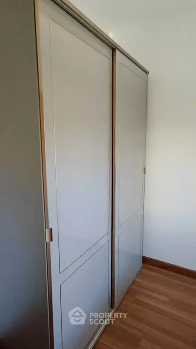 Spacious built-in wardrobe with sleek sliding doors in modern apartment.