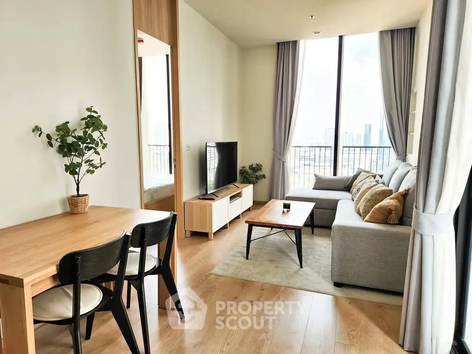 Modern living room with large windows and stylish furniture in a high-rise apartment.