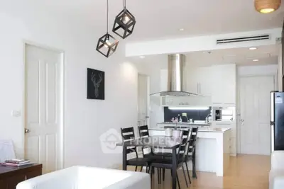 Modern open-layout kitchen and dining area with stylish lighting and sleek white cabinetry.