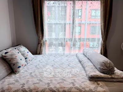 Cozy bedroom with stylish bedding and city view through large window.