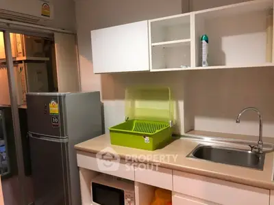 Modern kitchen with sleek cabinetry and stainless steel fridge, featuring a compact and efficient design.