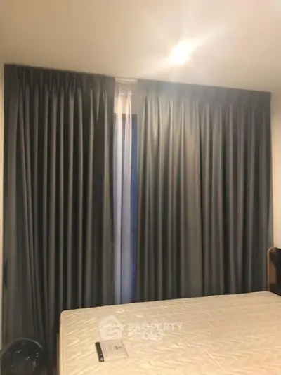 Cozy bedroom with elegant curtains and comfortable mattress, perfect for restful nights.