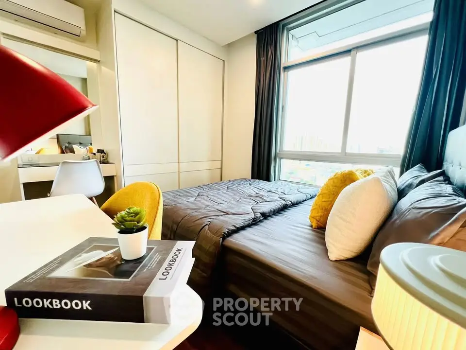 Modern bedroom with large window, stylish decor, and cozy bedding in a high-rise apartment.
