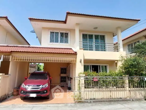 Charming two-story house with carport and lush greenery in a serene neighborhood.