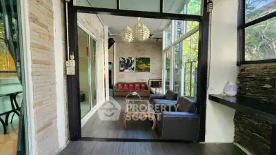 Chic living room with modern decor and large windows overlooking lush greenery.