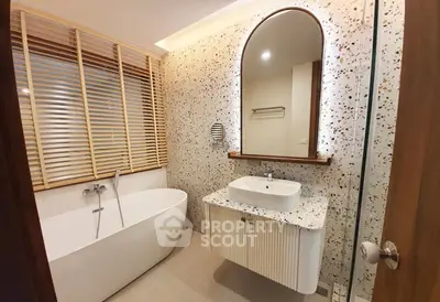 Modern bathroom with terrazzo wall, freestanding bathtub, and stylish vanity