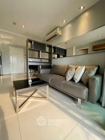 Modern living room with sleek furniture and air conditioning, featuring a stylish sofa and glass coffee table.