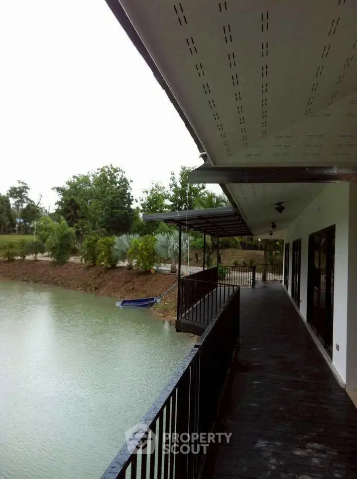 Stunning waterfront property with spacious balcony overlooking serene lake and lush greenery.