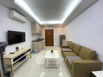 Modern living room with open kitchen, sleek furniture, and bright lighting.