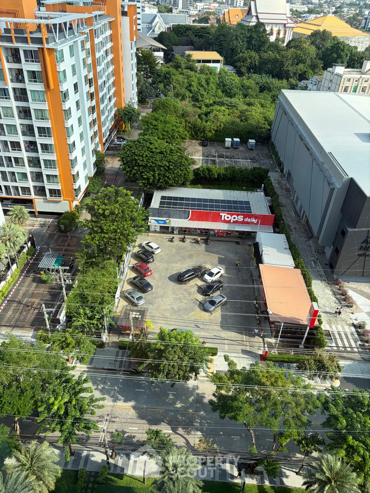 Aerial view of a modern residential building with adjacent parking and greenery.