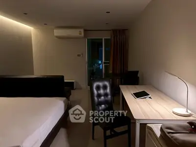 Modern bedroom with desk and tablet, featuring ambient lighting and sleek furnishings.