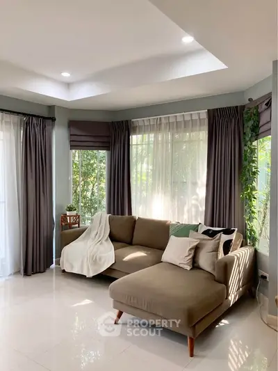 Bright and spacious living room with modern decor and large windows offering lush garden views.