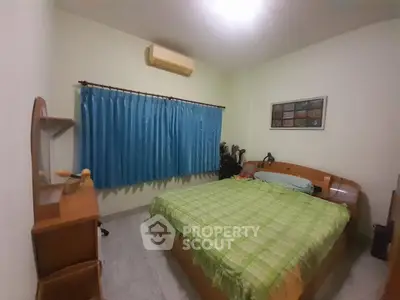 Cozy bedroom with green plaid bedding and blue curtains, featuring a wooden desk and wall art.