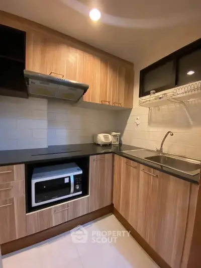 Modern kitchen with wooden cabinets and sleek appliances in a cozy layout.