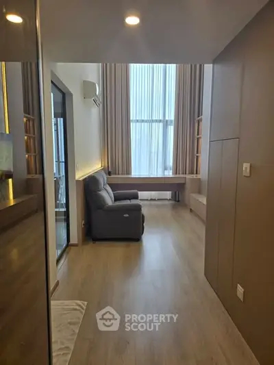 Modern living room with high ceilings and sleek design, featuring a cozy armchair and large windows.