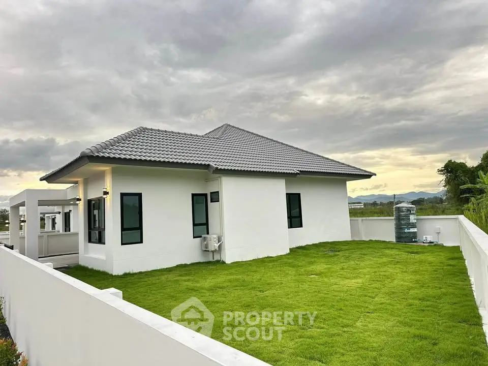 Modern single-story house with spacious green lawn and scenic mountain views.