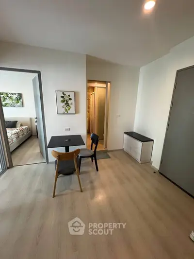 Modern apartment interior with dining area and bedroom view, featuring sleek furniture and minimalist decor.