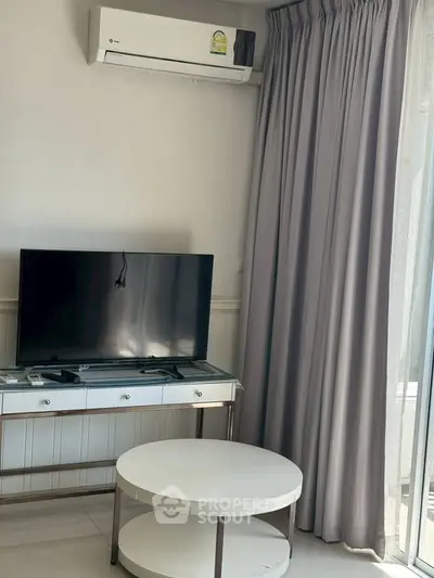 Modern living room with air conditioning and TV, featuring elegant curtains and a stylish coffee table.