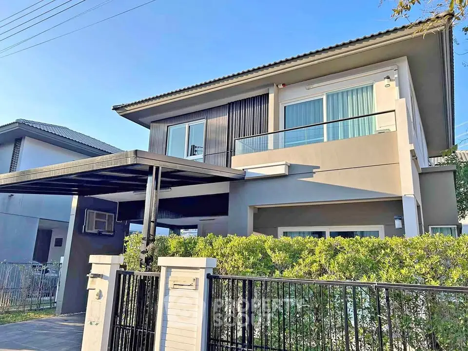 Modern two-story house with balcony and gated entrance in a suburban neighborhood.