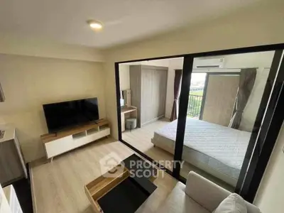 Modern apartment interior with living room and bedroom, featuring sleek furniture and large windows.