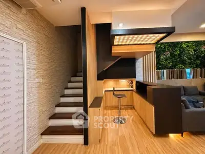 Modern living room with stylish staircase and cozy seating area, featuring wooden accents and ambient lighting.
