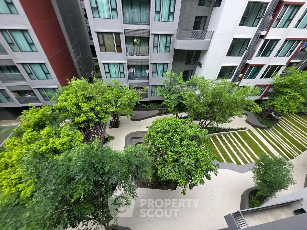 Modern apartment building with lush green courtyard and landscaped garden view.