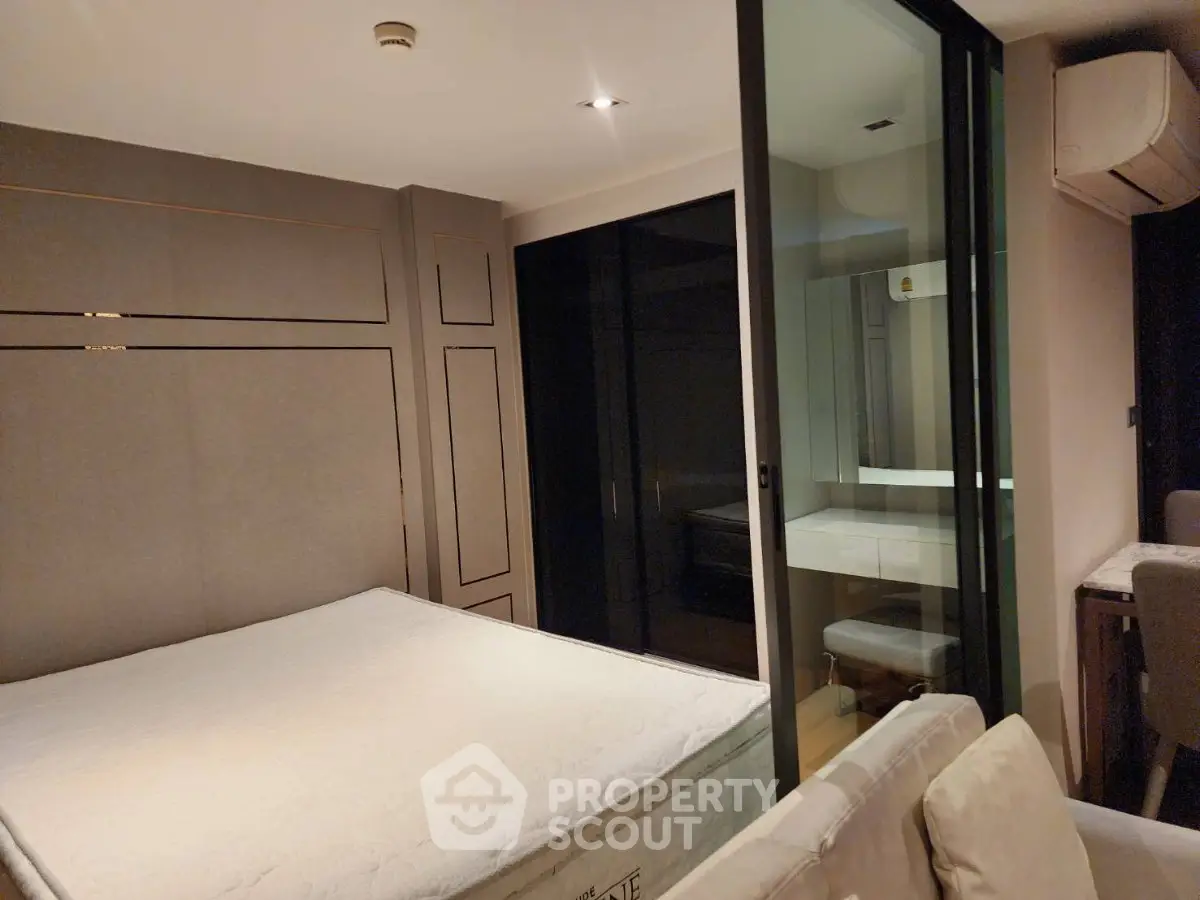Modern bedroom with sleek design and glass partition, featuring a comfortable bed and stylish decor.