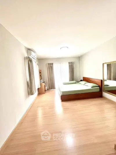 Spacious bedroom with wooden flooring and large mirror for modern living.
