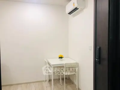 Minimalist dining area with white table and chairs under air conditioning unit.