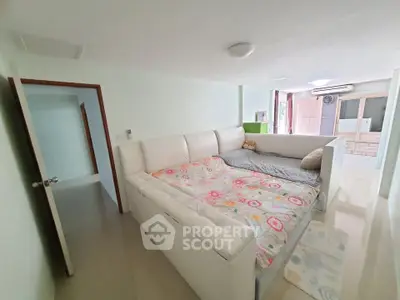 Spacious bedroom with modern white furniture and floral bedding in a bright apartment.