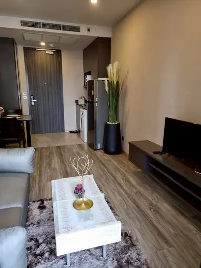 Modern living room with sleek furniture and open kitchen layout.