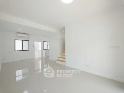 Spacious modern living room with glossy tile flooring and staircase