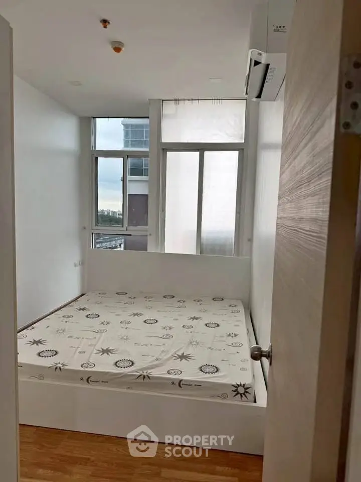Modern bedroom with large windows and wooden flooring in a high-rise apartment.