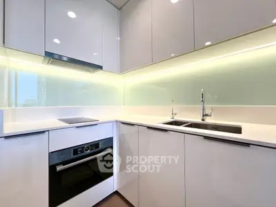 Modern kitchen with sleek cabinetry and built-in oven in a stylish apartment.