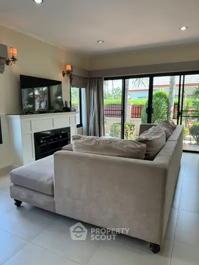 Spacious living room with elegant sofa and garden view through large windows.