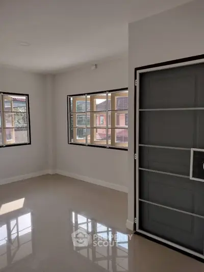 Spacious sunlit room with large windows and glossy floor in modern home.