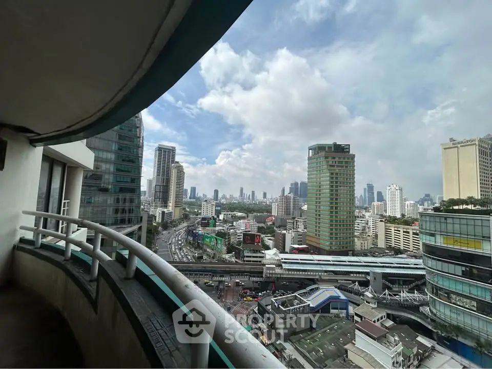 Stunning cityscape view from a high-rise balcony overlooking urban skyline and bustling streets.