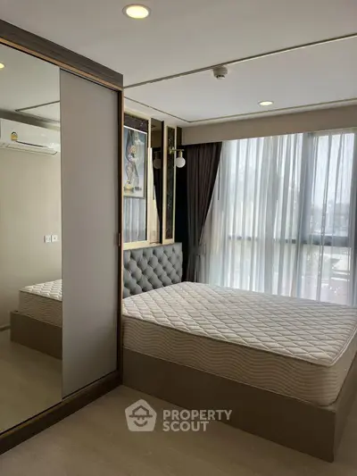 Modern bedroom with large window and stylish decor in a contemporary apartment.