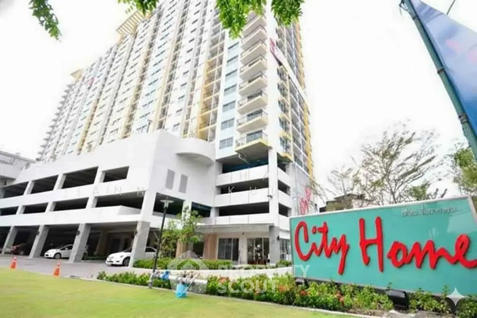 Modern high-rise building with City Home sign and lush green landscaping.