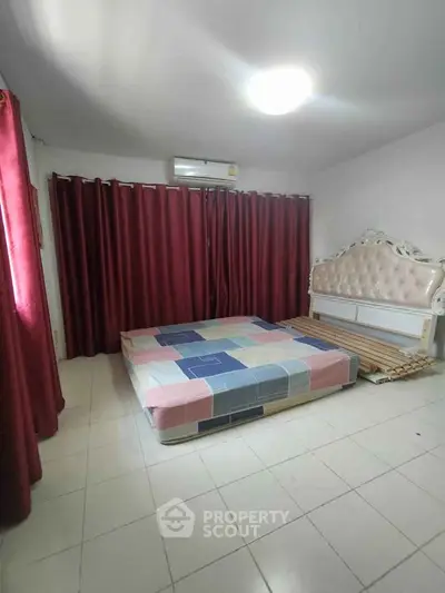 Spacious bedroom with elegant bed frame and vibrant curtains, perfect for a cozy retreat.