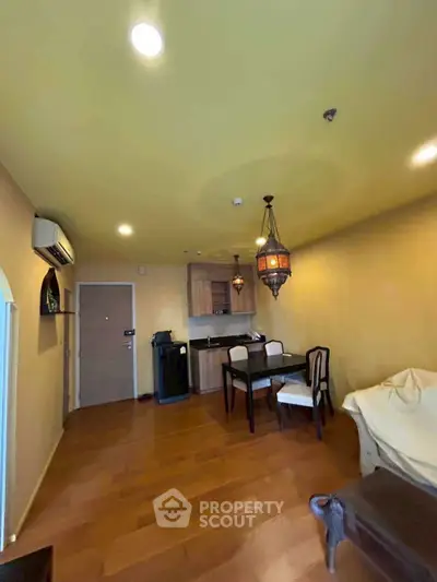 Charming living room with warm lighting and elegant dining area, featuring wooden flooring and stylish decor.