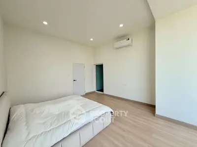 Spacious minimalist bedroom with modern air conditioning and cozy bed in a bright apartment.
