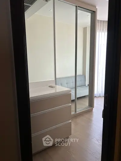 Modern apartment interior with sleek furniture and mirrored closet doors.