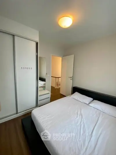 Modern bedroom with sleek design, featuring a comfortable bed and built-in wardrobe.