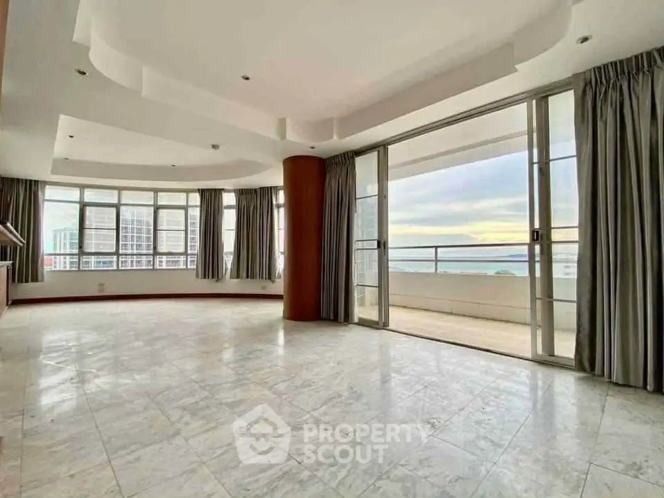 Spacious living room with ocean view and large balcony access, featuring elegant marble flooring.