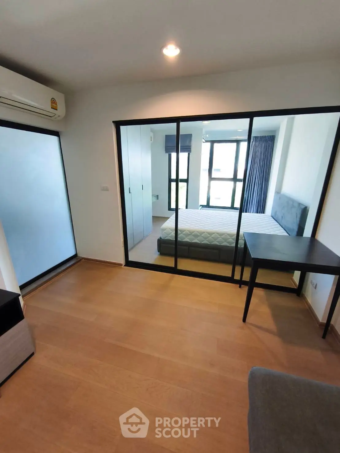 Modern bedroom with glass partition and wooden flooring in a stylish apartment